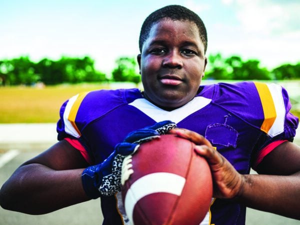 Black teen holding a football