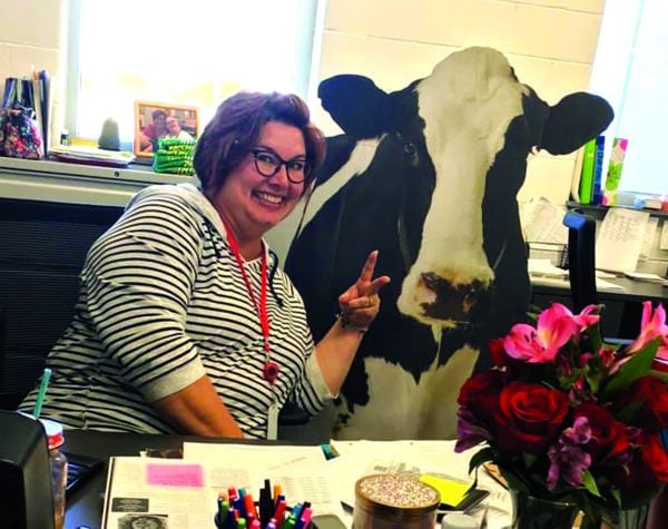 Anna Fails making a peace sign in front of a cardboard cutout of a cow