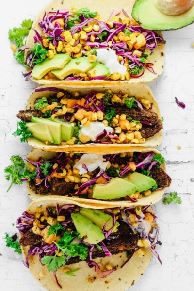 Four corn tacos with corn, avocado, black beans, cilantro