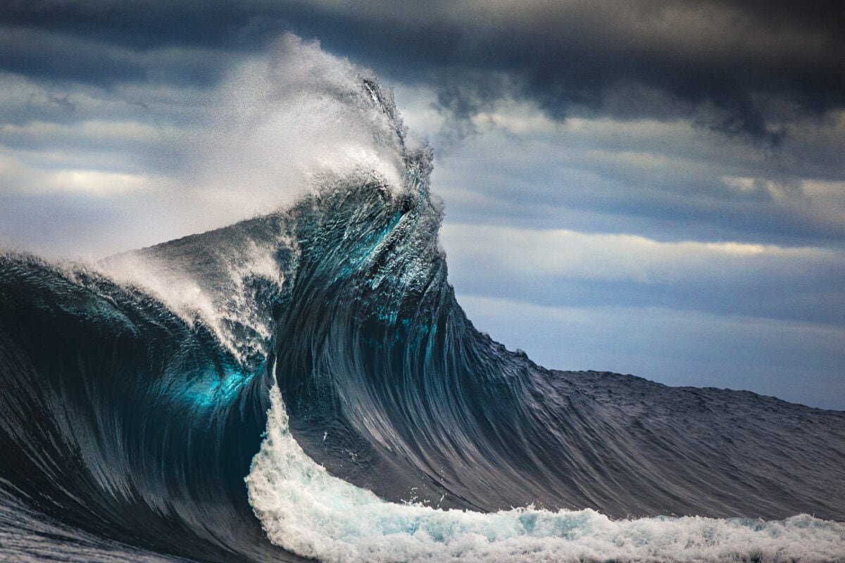 Tall powerful cross ocean wave breaking during a dark, stormy evening.