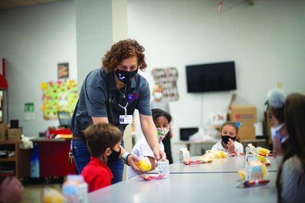 Laura Bounds assists school children with food at a table