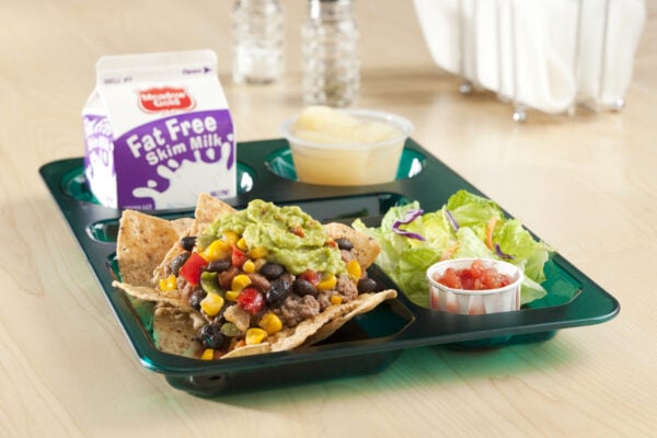 Nachos with milk, salad and fruit on a lunch tray