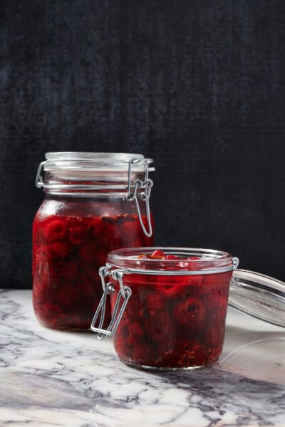 Pickled raspberries in mason jars with a black background