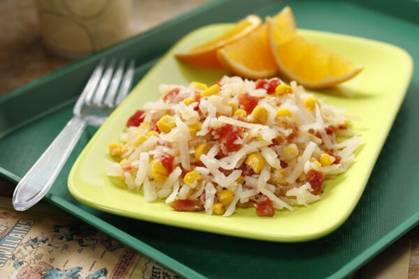 Tomato and corn hash browns on a light green plate with orange slices, all on a green tray