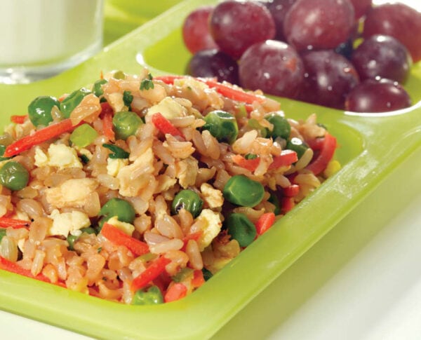 Fried rice on a green tray with grapes and a glass of milk