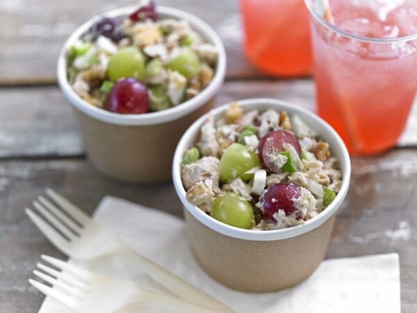 Two cups of tuna salad with grapes on a table with two forks