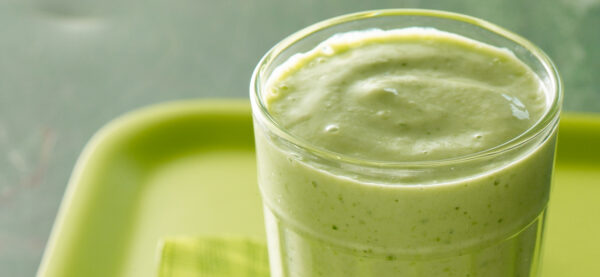 Green smoothie in a clear class sitting on a green plate