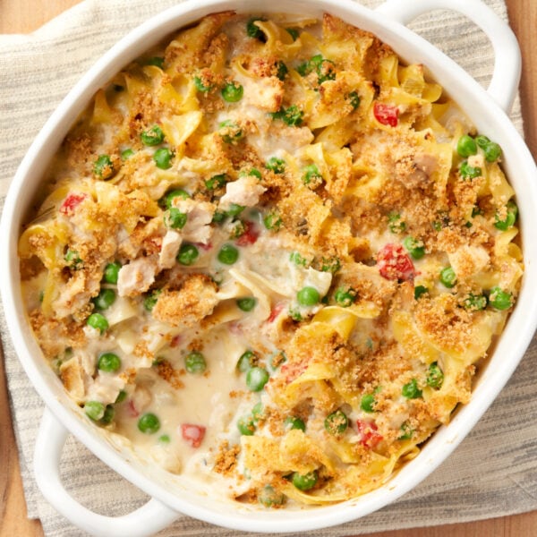 Tuna noodle casserole with peas and tomatoes in a white dish