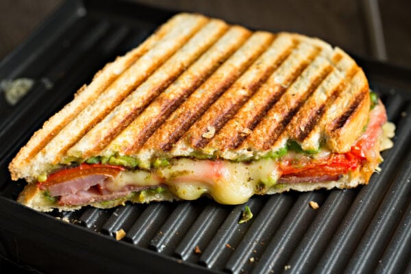 Half of a grilled sandwich made with ham, cheese, tomato and avocado