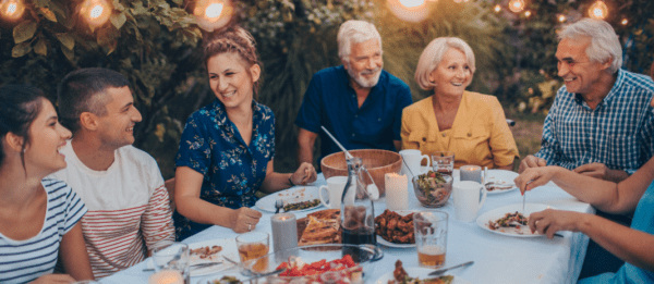 A group of six people ranging in age sitting around a table and eating together