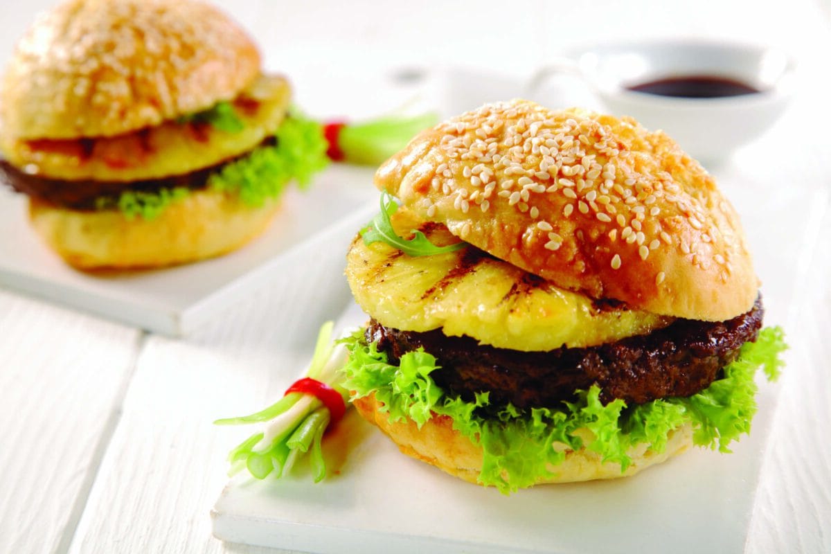 a hamburger with lettuce and pineapple on a bun