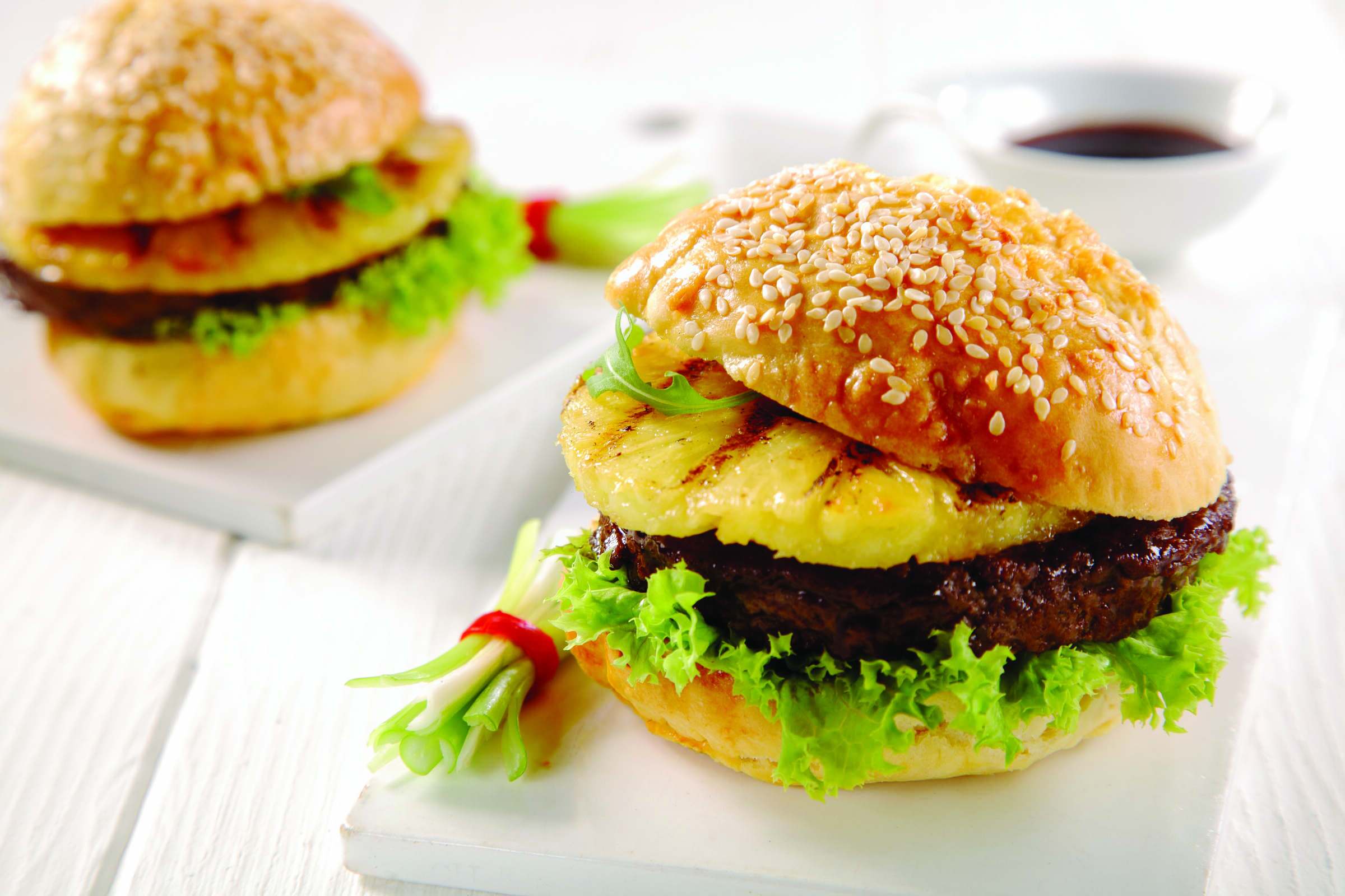 a hamburger with lettuce and pineapple on a bun