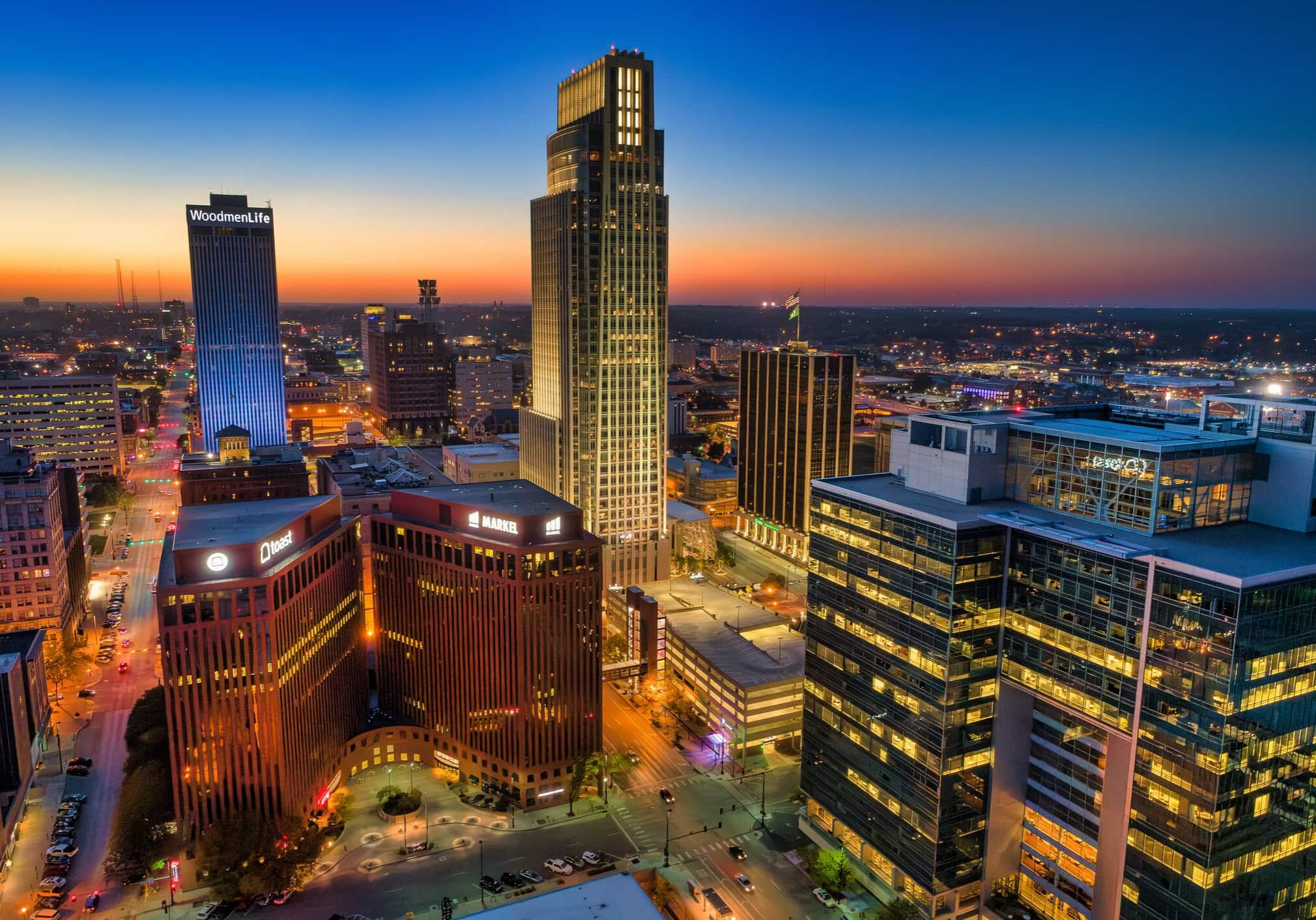 Aerial of Downtown Omaha at dusk with beautiful city lights and sunset colors.